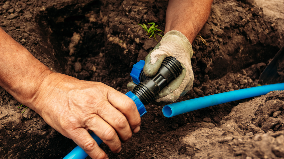 a man is installing a hose in the dirt .